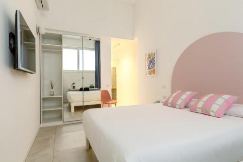a white bedroom with a white bed and a room with a view at Ravebility - self check-in in Quartu SantʼElena