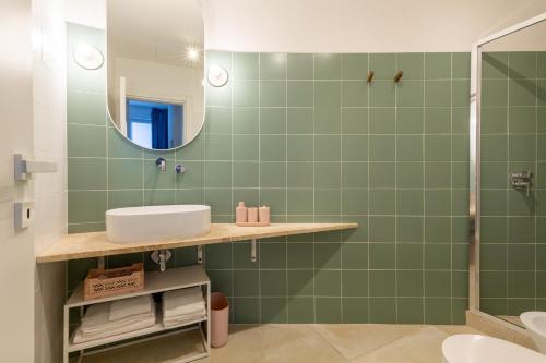 a green bathroom with a sink and a mirror at Ravebility - self check-in in Quartu SantʼElena