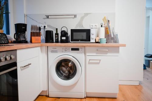 a kitchen with a washing machine under a counter at Sepperls Stubn Apartment - PETS no extra cost - Bad Goisern - 24-hours Self check-in in Bad Goisern