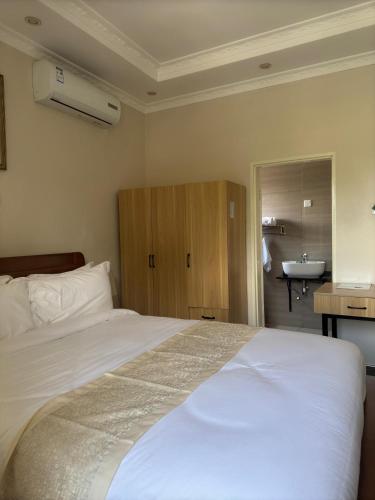 a bedroom with a large white bed and a sink at Eleganciana Lodges Limited in Lusaka