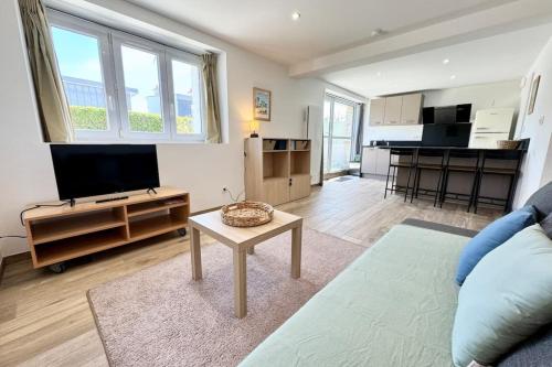 ein Wohnzimmer mit einer Couch, einem Fernseher und einem Tisch in der Unterkunft Joli appartement neuf Jardin 500 m des plages in Larmor-Plage