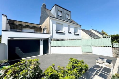 ein weißes Haus mit einer Garage und einem Zaun in der Unterkunft Joli appartement neuf Jardin 500 m des plages in Larmor-Plage