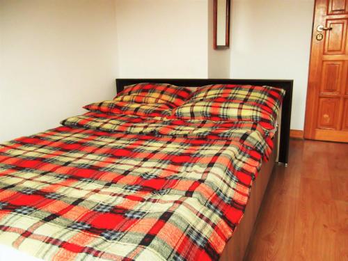 a bed with a plaid blanket on it in a bedroom at Dworek w Zieleni in Warsaw