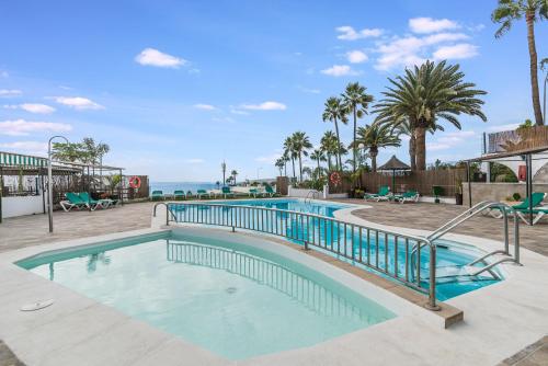 una piscina in un resort con palme di Corona Rosa Ocean View a Puerto Rico de Gran Canaria