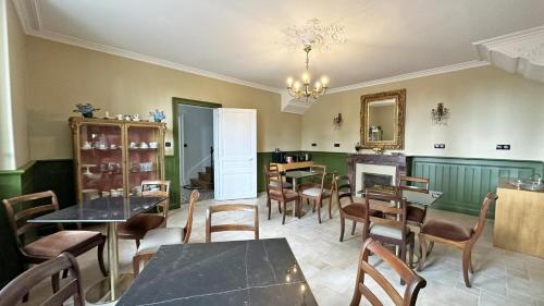 ein Esszimmer mit Tischen und Stühlen und einem Kamin in der Unterkunft Le manoir des perrieres in Rochechouart