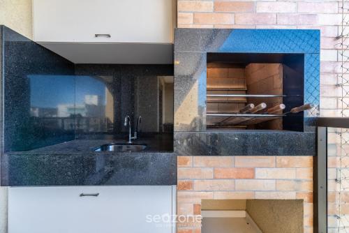a kitchen with a sink and a brick wall at DRL - Apartamentos a 300m da Praia de Bombinhas in Bombinhas