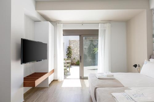 a white bedroom with a flat screen tv on a wall at Eveland Accessible Villas in Sfakaki