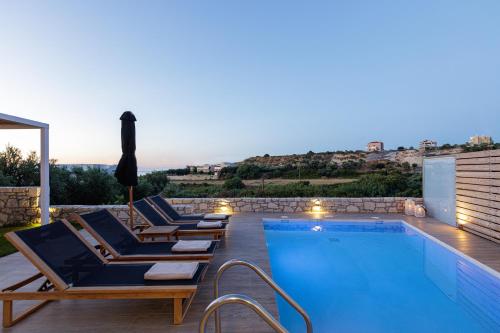 a swimming pool with lounge chairs next to a swimming pool at Eveland Accessible Villas in Sfakaki