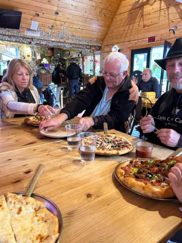 a group of people sitting at a table with pizzas at Carlo Creek Cabins in McKinley Park
