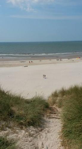 a beach with people on the sand and the ocean at Apartment Fanny fri adgang til svømmehal in Hvide Sande