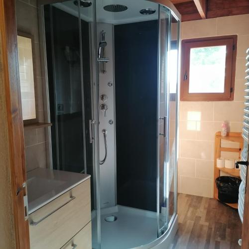 une douche avec une porte vitrée dans une salle de bain dans l'établissement Gîte T3 terrasse Chalet, à Puivert