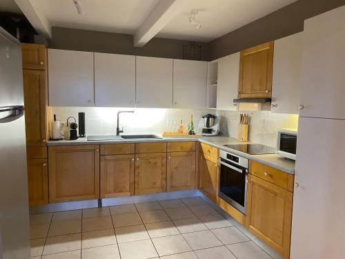 a kitchen with wooden cabinets and a white refrigerator at Gîte Le Chalet Suisse Dion in Beauraing