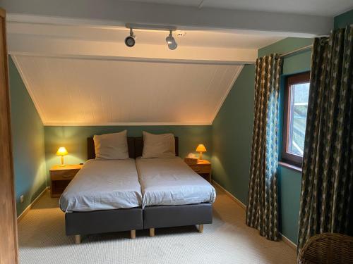a bedroom with a bed and two lamps and a window at Gîte Le Chalet Suisse Dion in Beauraing