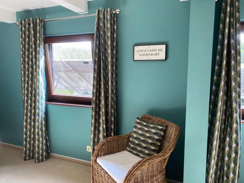 a wicker chair sitting in a room with a window at Gîte Le Chalet Suisse Dion in Beauraing