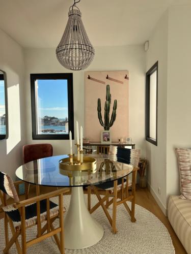 une salle à manger avec une table en verre et un cactus dans l'établissement La Corniche - vue mer à 180 degrés - centre ville, à Bandol