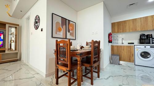 a kitchen with a table and chairs and a washing machine at Veridian Stay 2BR Oasis - Stylish & Modern in Abu Dhabi