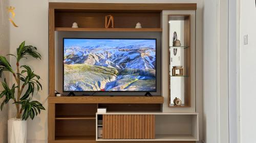 a television in a book shelf in a living room at Veridian Stay 2BR Oasis - Stylish & Modern in Abu Dhabi