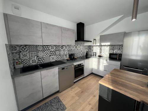 une cuisine avec des appareils en acier inoxydable et une table en bois dans l'établissement Maison au calme, à Villersexel