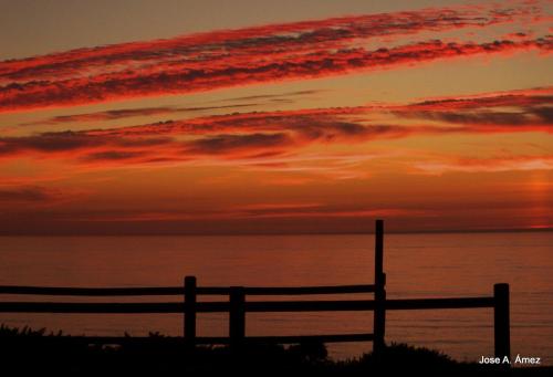 a sunset over the ocean with a fence in the foreground at HOTEL LA CASA DE LAS CAMELIAS in Busto