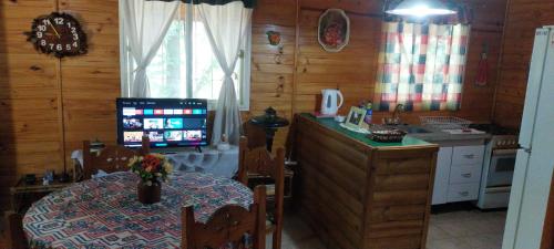 a kitchen with a table and a television in a room at Cabañas Villa Adler in Potrerillos