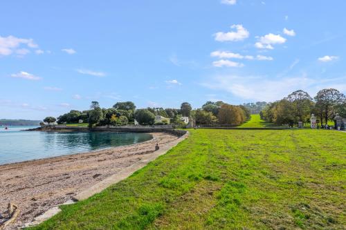 a grassy field next to a body of water at Seascape in Torpoint