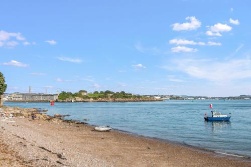 a boat in the water next to a beach at Seascape in Torpoint