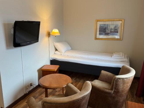 a room with a bed and two chairs and a tv at Park Hotel Vossevangen in Vossevangen