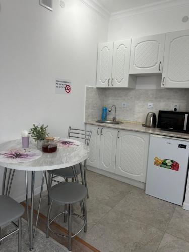 a kitchen with white cabinets and a table and chairs at Promenade Burabay in Borovoye
