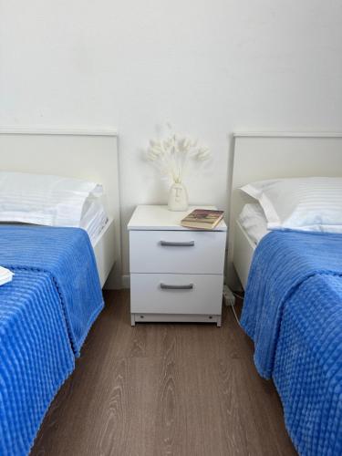 a bedroom with two beds with blue comforters and a night stand at Promenade Burabay in Borovoye