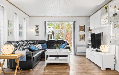 a living room with a black leather couch and a tv at 4 Bedroom Beautiful Home In Skjern in Skjern