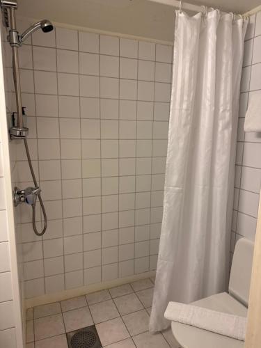 a bathroom with a shower with a white shower curtain at Park Hotel Vossevangen in Vossevangen
