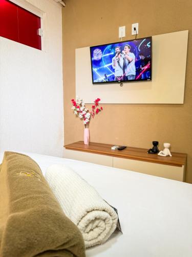 a bedroom with a bed with a tv on the wall at Hotel Leda Rafael in João Câmara