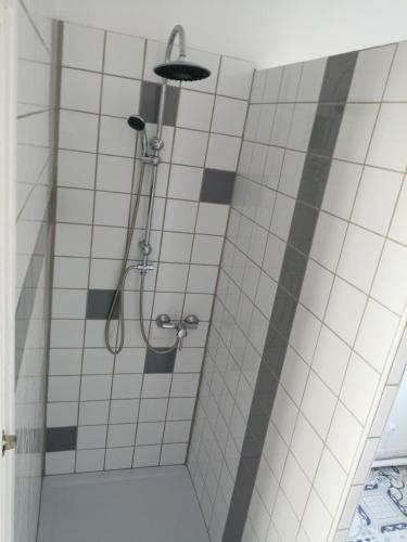 une douche dans une salle de bain avec du carrelage blanc dans l'établissement L'Héritage, à Abbeville