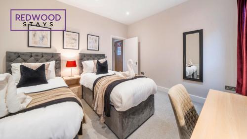 a bedroom with two beds and a table and a mirror at Newly Refurbished Everest Lodge Serviced Apartments for Contractors & Families, FREE WiFi & Netflix by REDWOOD STAYS in Farnborough