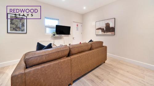 a brown couch in a living room with a tv at Newly Refurbished Everest Lodge Serviced Apartments for Contractors & Families, FREE WiFi & Netflix by REDWOOD STAYS in Farnborough