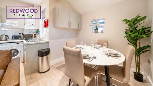 a kitchen and dining room with a white table and chairs at Newly Refurbished Everest Lodge Serviced Apartments for Contractors & Families, FREE WiFi & Netflix by REDWOOD STAYS in Farnborough