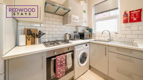 a kitchen with a sink and a washing machine at Newly Refurbished Everest Lodge Serviced Apartments for Contractors & Families, FREE WiFi & Netflix by REDWOOD STAYS in Farnborough