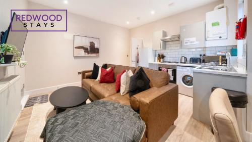 a living room with a couch and a kitchen at Newly Refurbished Everest Lodge Serviced Apartments for Contractors & Families, FREE WiFi & Netflix by REDWOOD STAYS in Farnborough