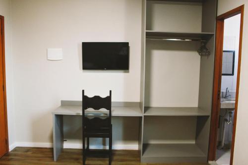 a desk with a chair and a television in a room at Hotel Pousada Del Rey in Macaé