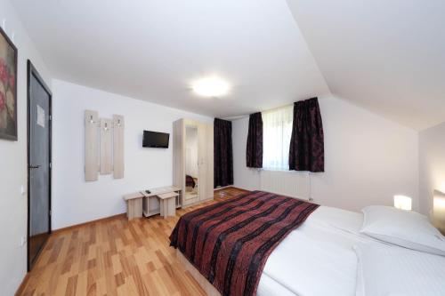a white bedroom with a large bed and a window at Casa Dintre Vai in Şimon