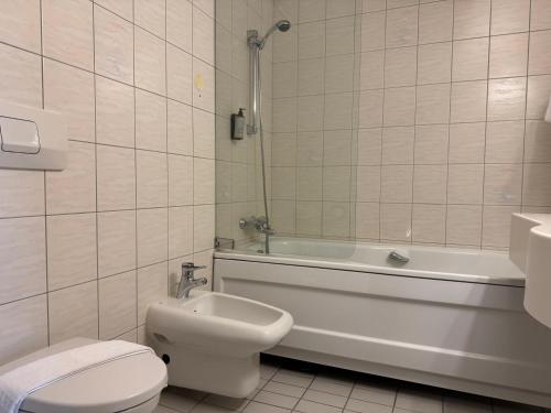 a bathroom with a toilet and a tub and a sink at Park Hotel Vossevangen in Vossevangen