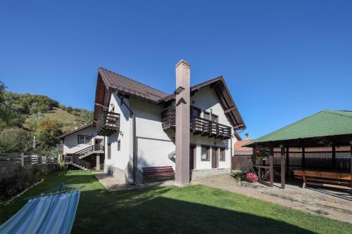 a house with a green roof and a grass yard at Casa Dintre Vai in Şimon