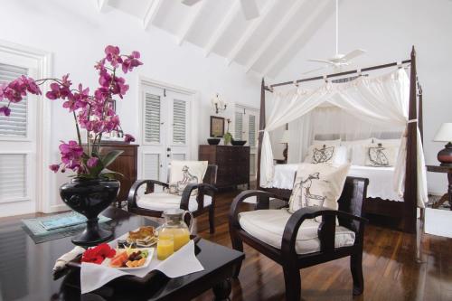 a bedroom with a bed and a table with a tray of food at The Inn at English Harbour in English Harbour Town