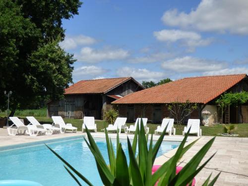 un complexe avec une piscine, des chaises et une maison dans l'établissement Ferme landaise dans un environnement privilégié, à Taller