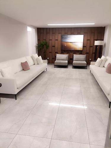 a living room with white couches and chairs at Residencial Acquamare in Praia Grande