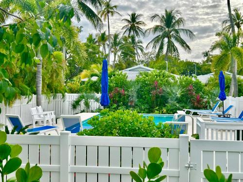 a white fence with chairs and umbrellas next to a pool at Castaway Island Vacation Bungalow in Islamorada