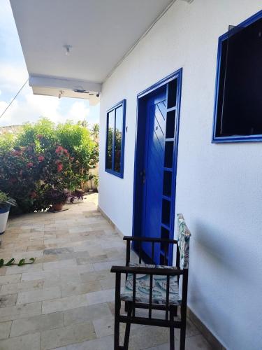a chair sitting outside of a house with a blue door at Ponta Negra Suites & Apart in Natal