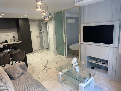 un salon avec un canapé et une télévision sur un mur dans l'établissement Apartment best position croisette martinez ! 150m from the beach completely renovated !, à Cannes