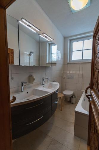 a bathroom with a sink and a tub and a toilet at Landhaus Flasch in Wagrain