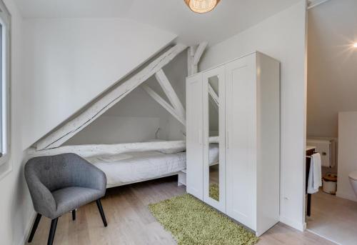 Cette chambre comprend un lit, une chaise et un miroir. dans l'établissement L'Atypique - Echappée sous les toits, à Toulouse